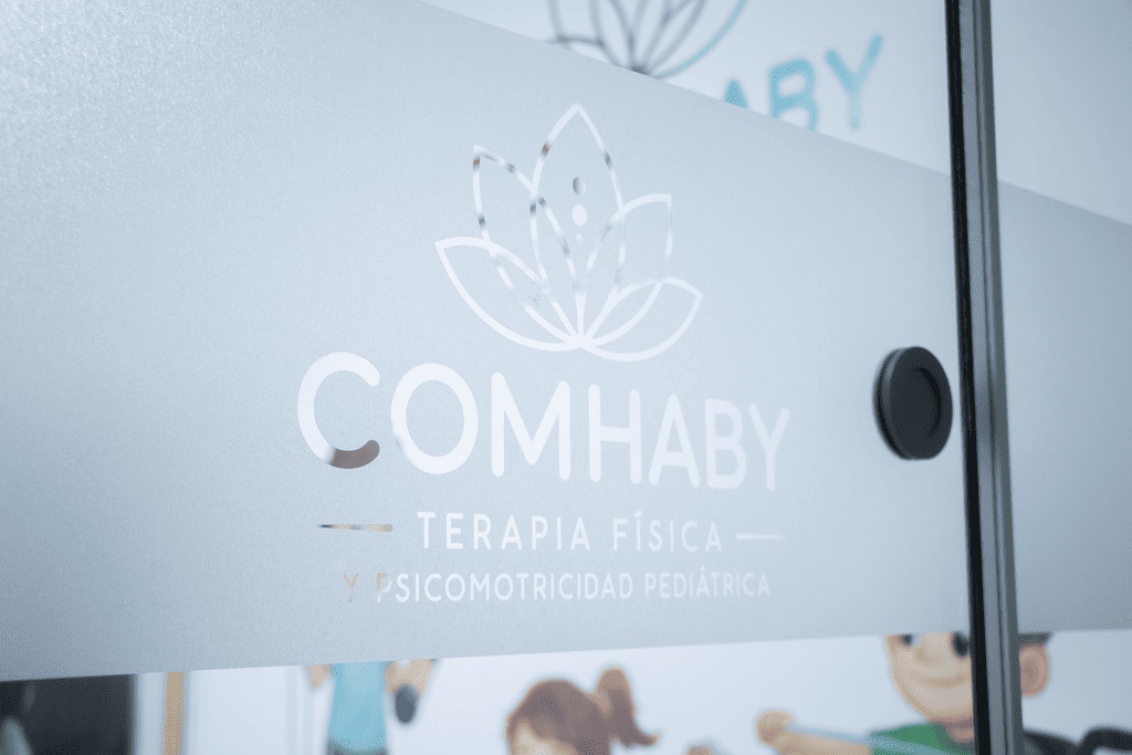 Entrada de COMHABY: puerta de vidrio con el logotipo esmerilado del centro