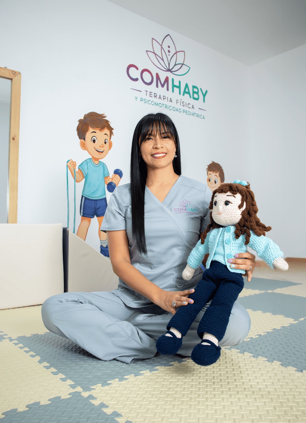 Retrato de la Lic. Betzy Muñoz sosteniendo una muñeca terapéutica en la sala de COMHABY